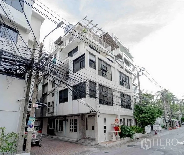 带办公室的家 出租在Bang Rak, Bangkok - 安静小巷中的白色多层商住两用楼，黑色窗框并设屋顶露台的转角外观。