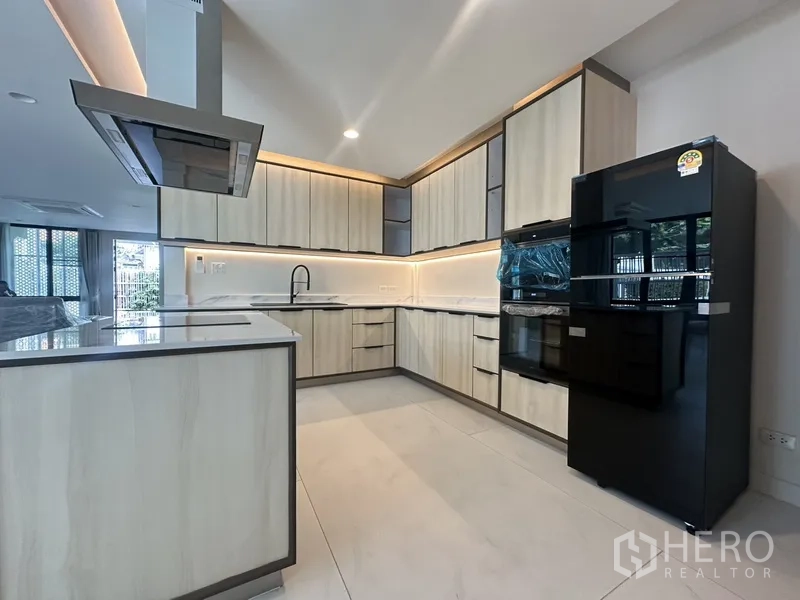 联排别墅 出租在Watthana, Bangkok - 现代L形厨房，浅木柜、黑色冰箱与嵌入式烤箱