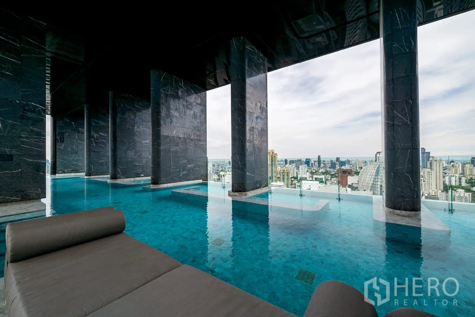 Condominium for rent in Watthana, Bangkok - Infinity-edge pool with loungers overlooking the skyline.