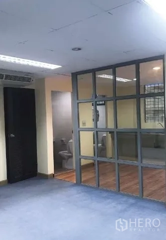 Office Space for rent in Bang Rak, Bangkok - Open-plan office with glass partition and visible restroom entrance.