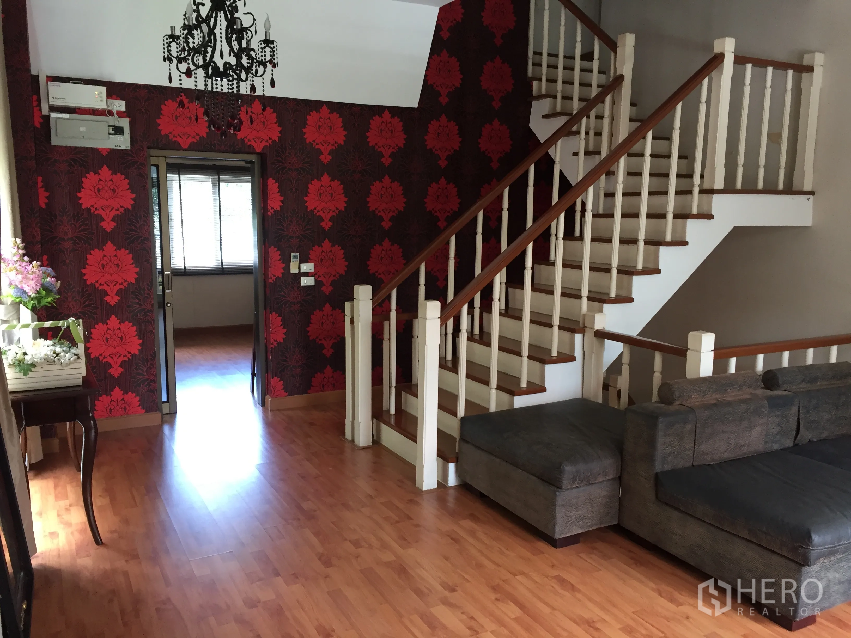 Townhouse for rent or sale in Bueng Kum, Bangkok - Stair hall with bold red patterned feature wall, chandelier and wood flooring.