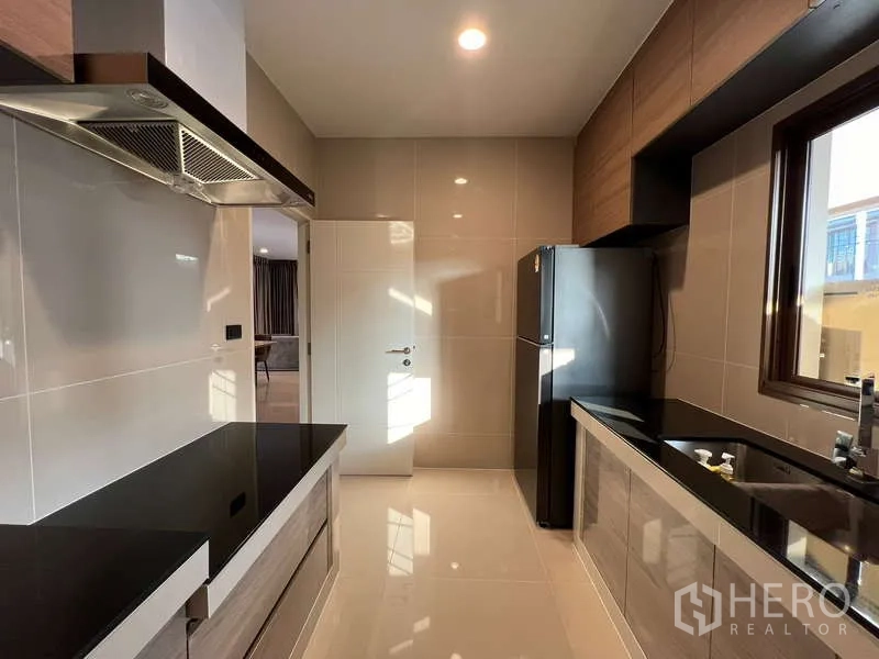 Detached House for rent in Bang Kapi, Bangkok - Kitchen from opposite angle with fridge, double sinks and ample cabinetry.