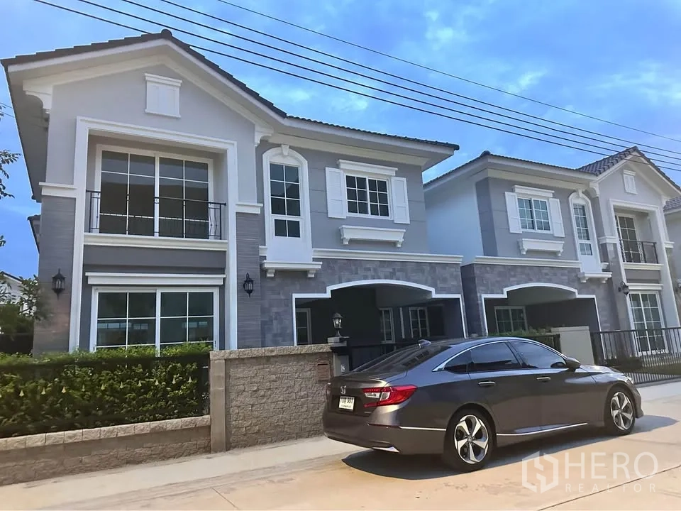 Semi-detached House for rent in Mueang Samut Prakan, Samut Prakan - Two-storey semi-detached house with balcony, large windows, and front parking area.