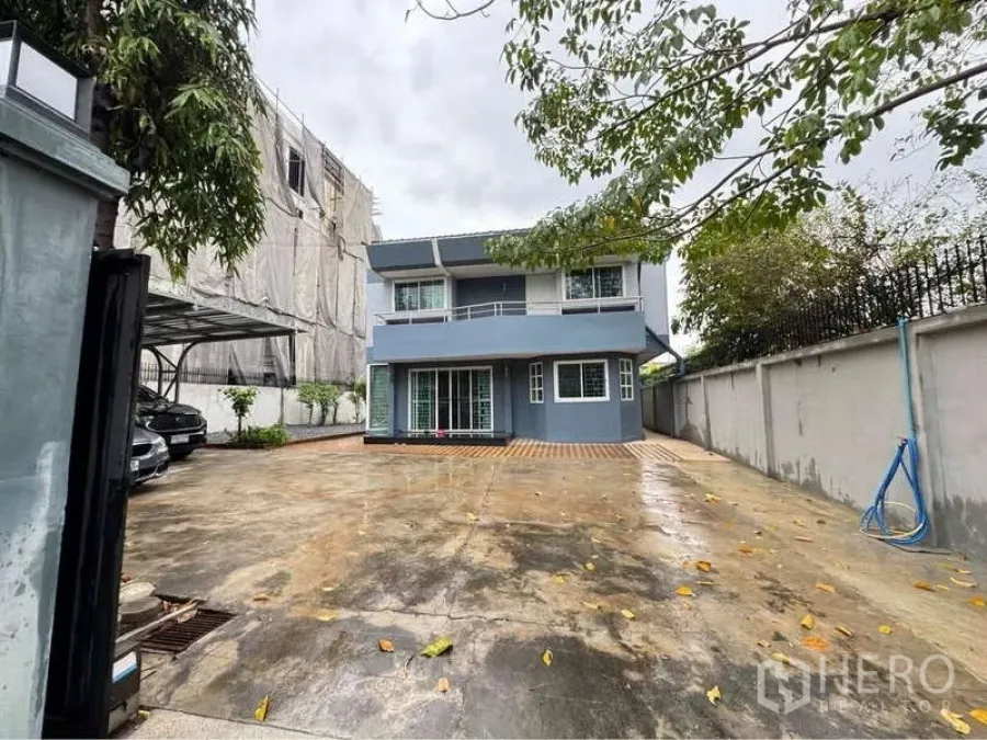 独立式住宅 出租在Suan Luang, Bangkok - 两层独栋别墅，前院宽阔混凝土车道，侧边有车棚与大门。