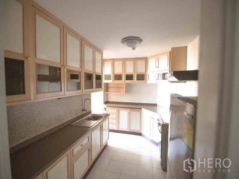 Condominium for rent in Watthana, Bangkok - Separate kitchen with extensive upper cabinets, stone countertops, sink, and natural light.