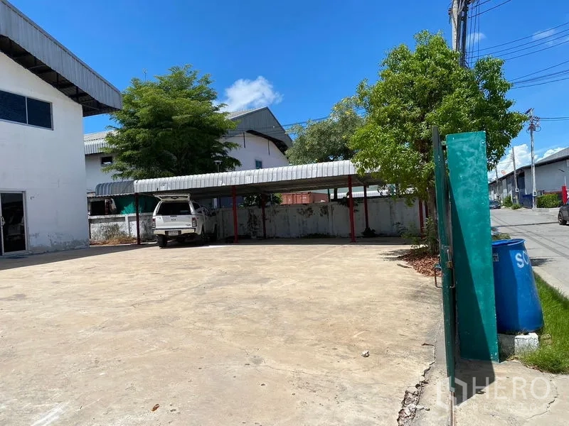 工厂 出租或出售在Bang Phli, Samut Prakan - 混凝土院坪配带顶停车位，旁有树荫。