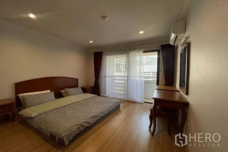 公寓 出租在Watthana, Bangkok - 卧室配大床、木地板、书桌及通向阳台的推拉门。