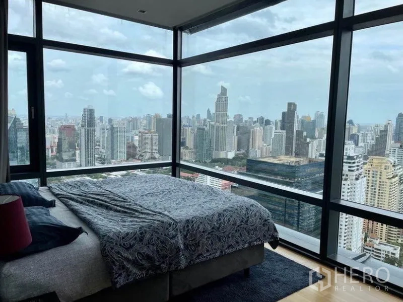 Condominium for sale in Ratchathewi, Bangkok - Corner bedroom wrapped in glass showcasing sweeping views of Bangkok’s skyline.