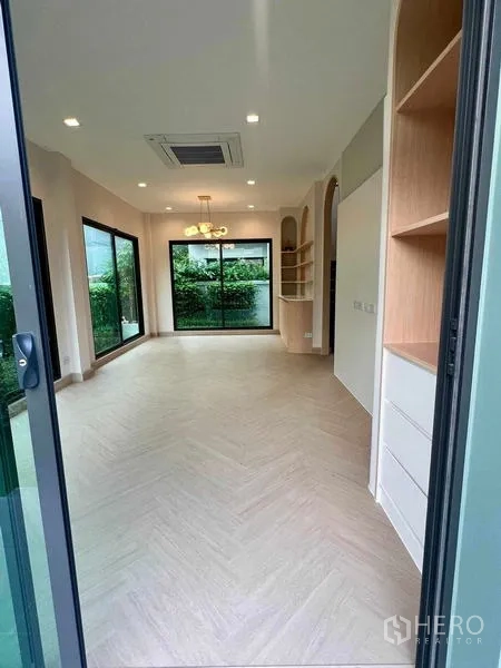 Detached House for sale in Bang Kruai, Nonthaburi - Entry view to an airy living area with large glass sliders, herringbone floors and built-in cabinetry.