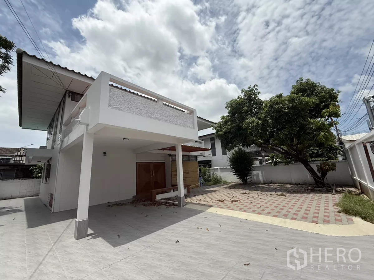 Detached House for rent in Phra Khanong, Bangkok - Two-storey detached house exterior with covered carport, paved driveway and a mature tree.