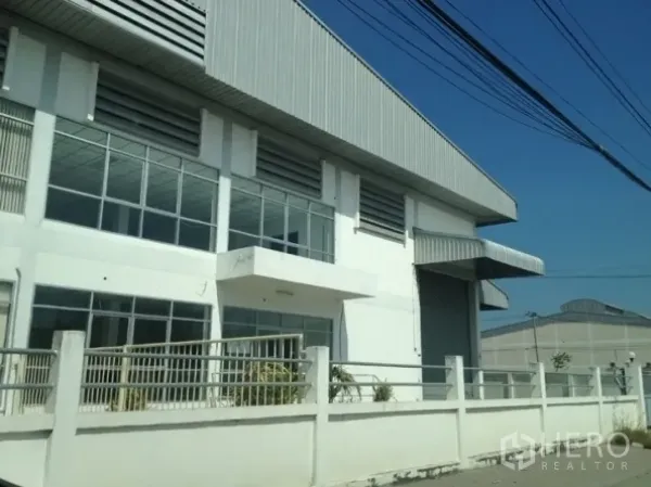货栈 出租在Samut Prakan - 位于北榄府的仓库街景，围栏齐全，落地窗与宽幅卷帘门。