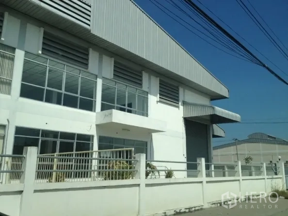 货栈 出租在Samut Prakan - 位于北榄府的仓库街景，围栏齐全，落地窗与宽幅卷帘门。
