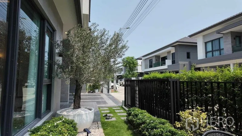บ้าน ให้เช่าหรือขายในBang Na, Bangkok - มุมมองสวนหน้าและถนนในหมู่บ้านที่รายล้อมด้วยบ้านสไตล์โมเดิร์น