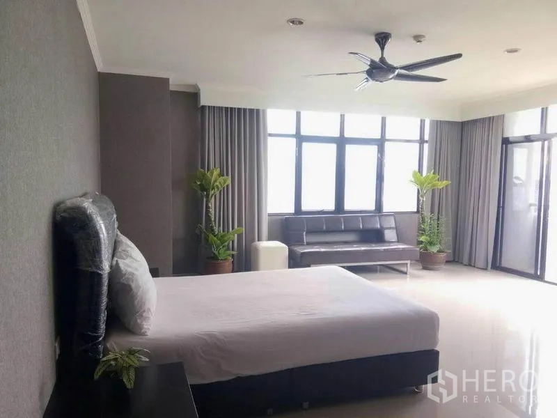 公寓 出租在Watthana, Bangkok - 超大卧室，落地窗与灰色窗帘，吊扇、沙发与绿植点缀