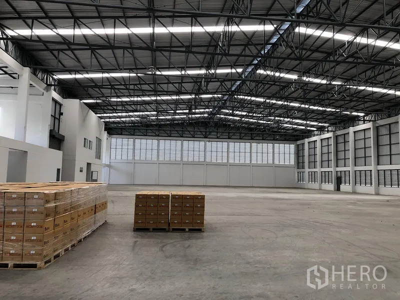 Factory for rent in Phra Nakhon Si Ayutthaya - Warehouse interior with pallets on a smooth concrete floor and high roof.