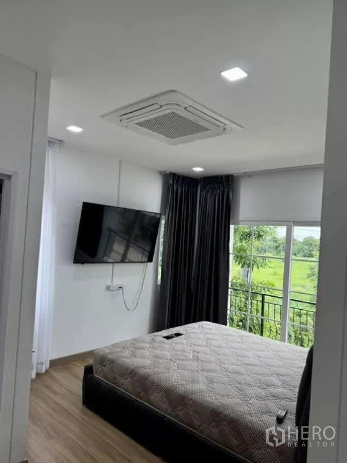 Detached House for rent in Thanyaburi, Pathum Thani - Another angle of the master bedroom with floor-to-ceiling windows and balcony door.