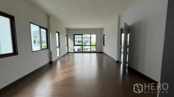 Detached House for sale in Bang Phli, Samut Prakan - Bright upper-floor room with wood flooring and large windows in the Bang Phli detached house.