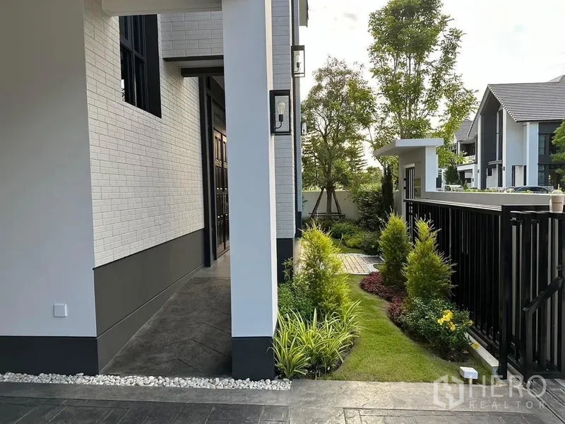 Detached House for rent or sale in Bang Phli, Samut Prakan - Side walkway beside the house with landscaped garden beds, shrubs and a modern fence.