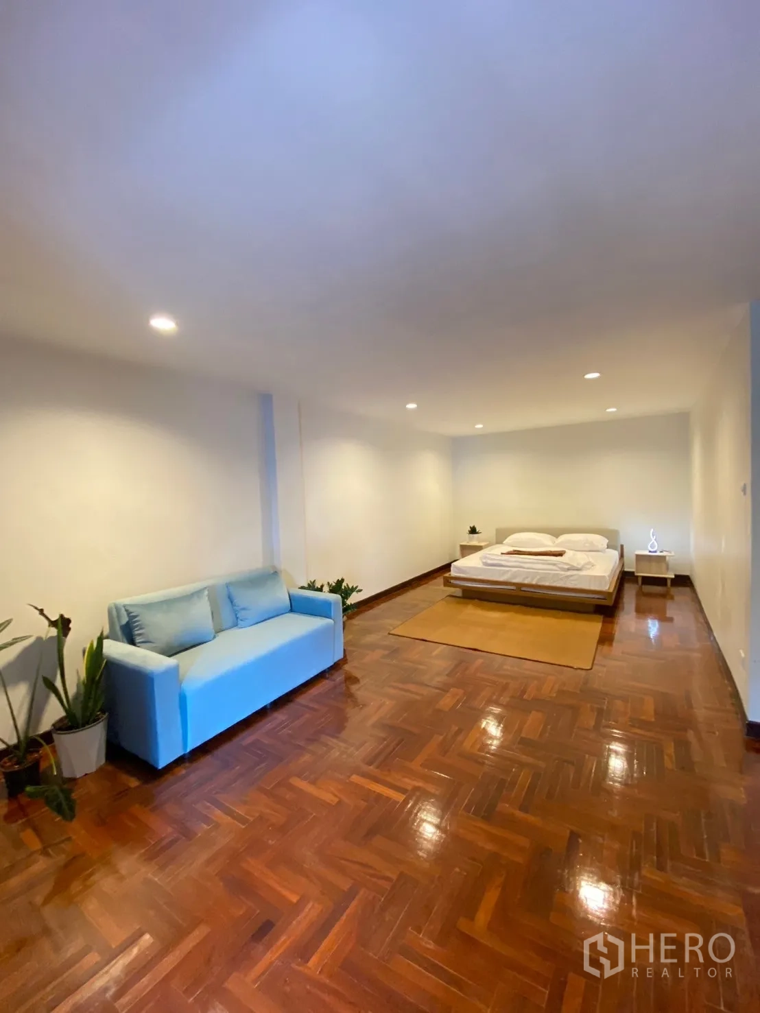 家庭办公室 for rent in Watthana, Bangkok - 大卧室内有蓝色沙发与平台床，木拼地板