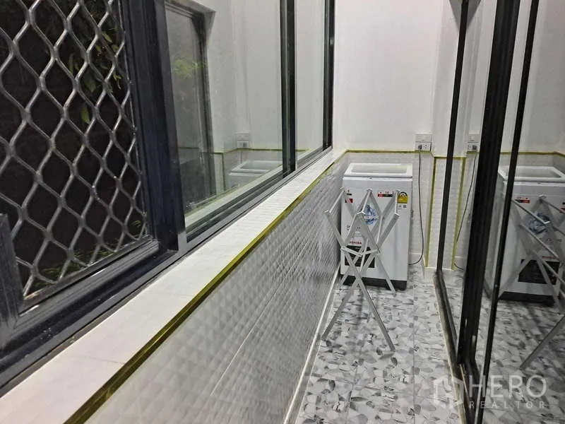公寓 出租在Khlong Toei, Bangkok - 封闭式生活阳台，配洗衣机、晾衣架与防盗窗格。