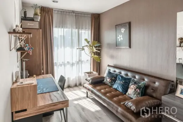 Condominium for rent in Sathon, Bangkok - Cozy second bedroom or study with a wooden desk, sofa bed, and full-height curtains.