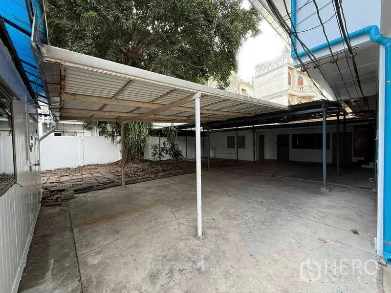 Detached House for rent in Watthana, Bangkok - Covered carport with metal roof and paved area next to the house.