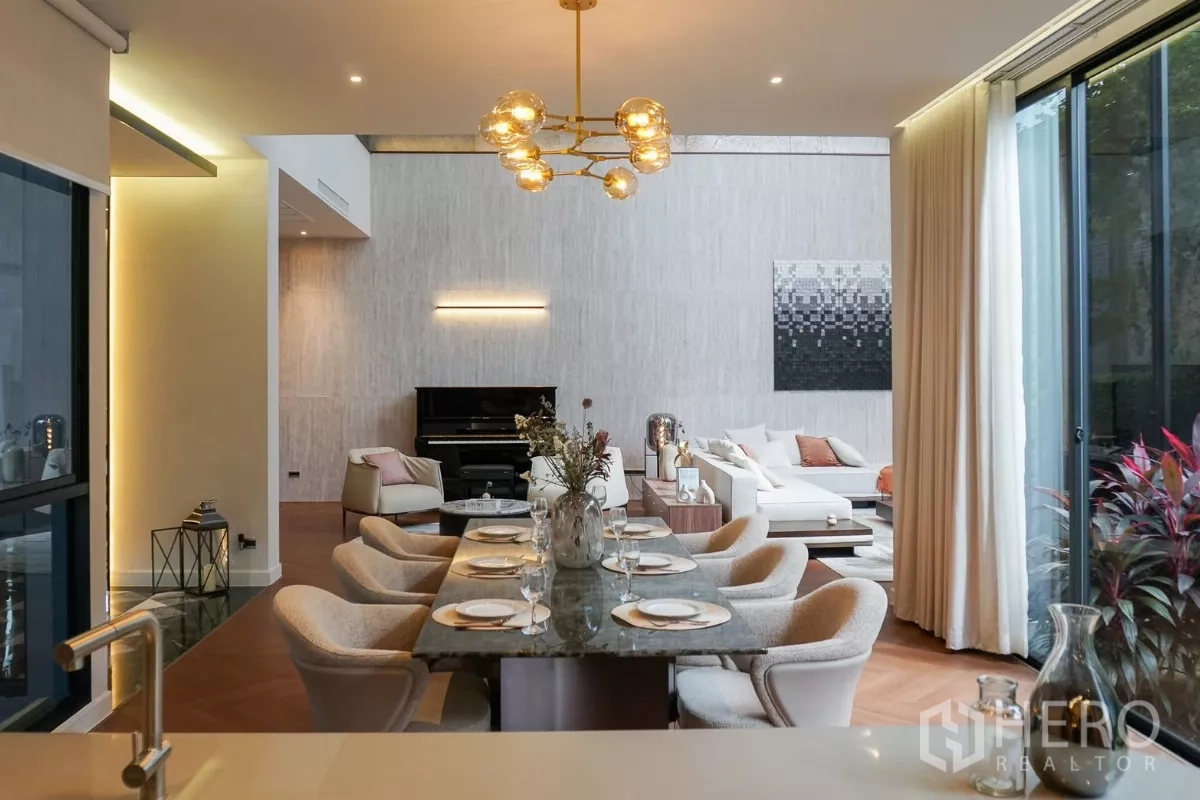 Detached House for rent or sale in Bang Kapi, Bangkok - Elegant dining area with marble table and gold chandelier, lounge and upright piano beyond.