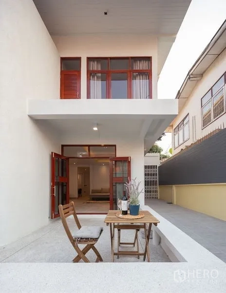 Detached House for sale in Chatuchak, Bangkok - Back terrace with folding French doors and a small outdoor table and chairs.