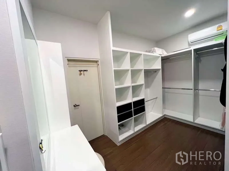独立式住宅 出售在Prawet, Bangkok - 步入式衣帽间，白色格柜、挂衣区与梳妆台，配空调。