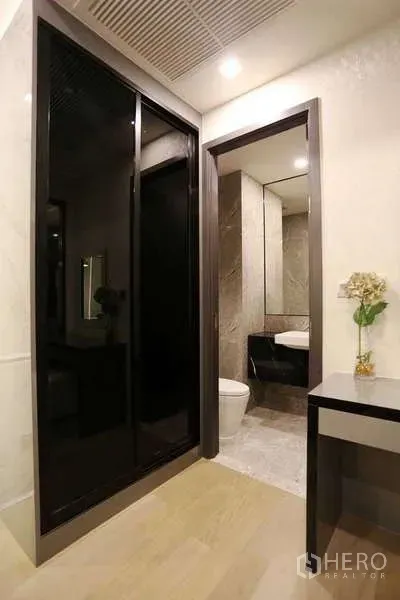 公寓 出租在Watthana, Bangkok - 玄关走廊，黑色玻璃推拉衣柜、梳妆台与通往浴室的门