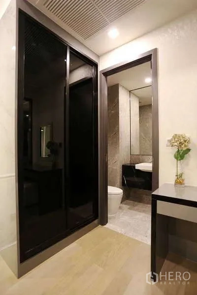 公寓 出租在Watthana, Bangkok - 玄关走廊，黑色玻璃推拉衣柜、梳妆台与通往浴室的门
