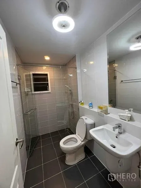 独立式住宅 出租或出售在Lat Krabang, Bangkok - 明亮浴室，玻璃淋浴间、洗手盆与坐便器。