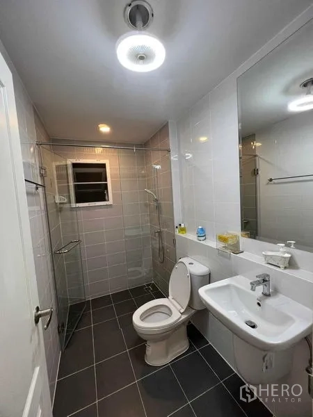 独立式住宅 出租或出售在Lat Krabang, Bangkok - 明亮浴室，玻璃淋浴间、洗手盆与坐便器。