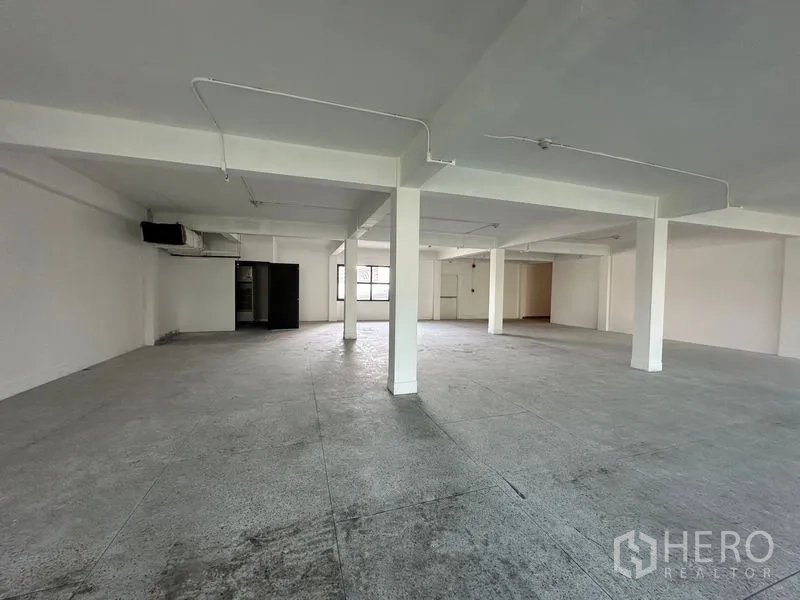 Office Space for rent in Khlong Toei, Bangkok - Bright empty office floorplate with windows on two sides and a marked emergency exit door.
