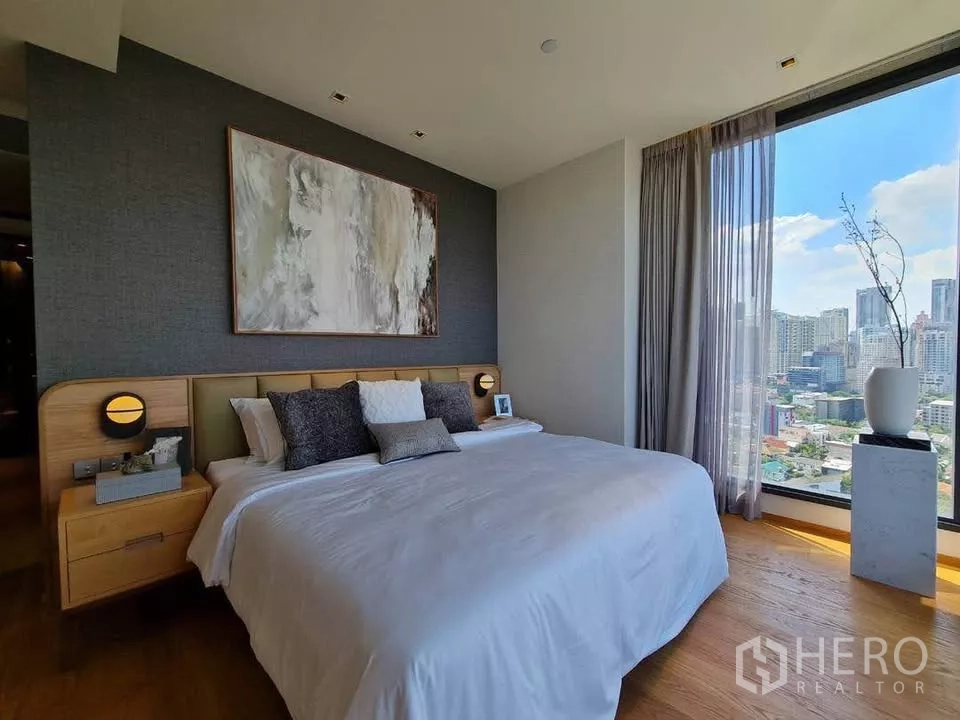 Condominium for rent or sale in Khlong Toei, Bangkok - Primary bedroom with king bed, bedside tables and corner windows showcasing daytime city views.