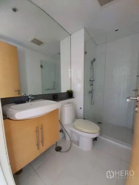 Condominium for rent in Watthana, Bangkok - Bright bathroom with vanity, toilet, and a glass walk‑in shower.