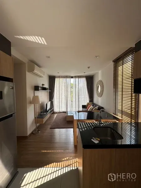 公寓 出租在Watthana, Bangkok - 开放式客厅与厨房岛台，木地板，大落地窗与纱帘通向阳台