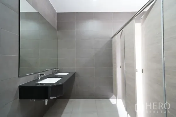 Warehouse for rent in Khlong Luang, Pathum Thani - Modern restroom with long vanity, dual sinks, large wall mirror, and tiled stalls.