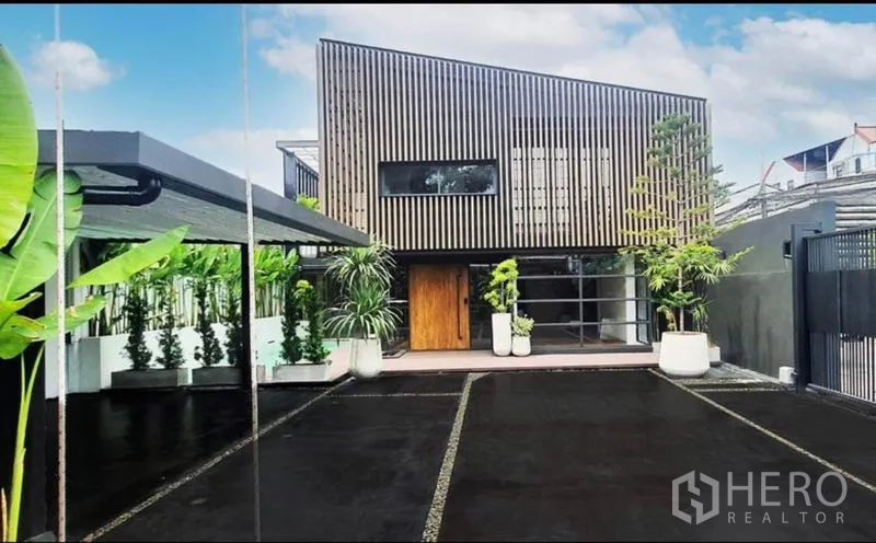 带办公室的家 出租或出售在Khlong Toei, Bangkok - 前方车道与停车区通往两层家庭办公楼，木格立面醒目。
