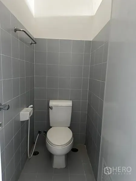 Factory for rent in Pathum Thani - Private toilet cubicle with bidet spray and grey wall tiles.