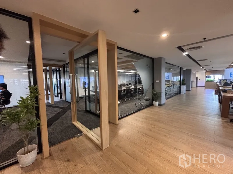 Office Space for rent in Bang Rak, Bangkok - Entrance to glass meeting rooms beside an open-plan workspace with wood floors.