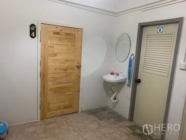 Shophouse for rent in Khlong Toei, Bangkok - Common area featuring a wooden room door, wall-mounted sink with mirror, and restroom entrance.