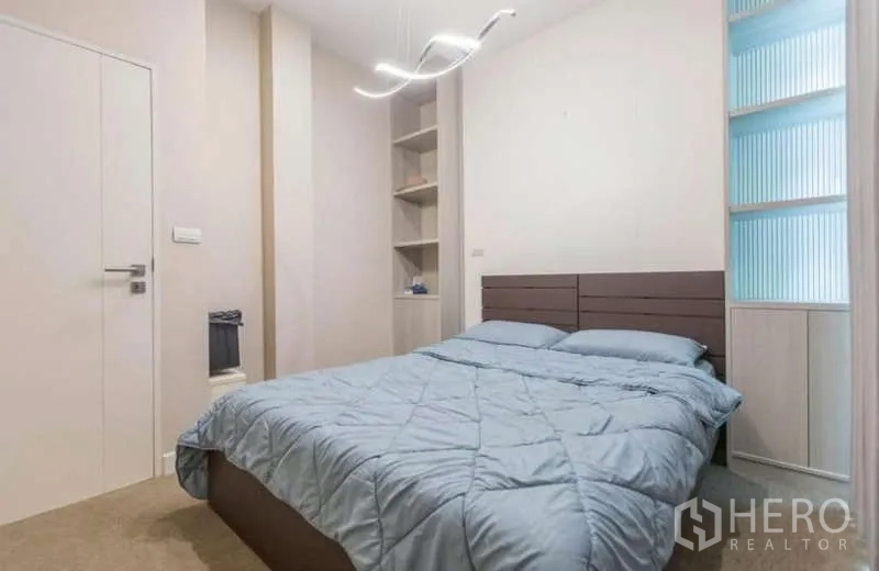 Detached House for rent or sale in Lat Phrao, Bangkok - Cozy bedroom with built-in shelves, soft pendant light and blue duvet.