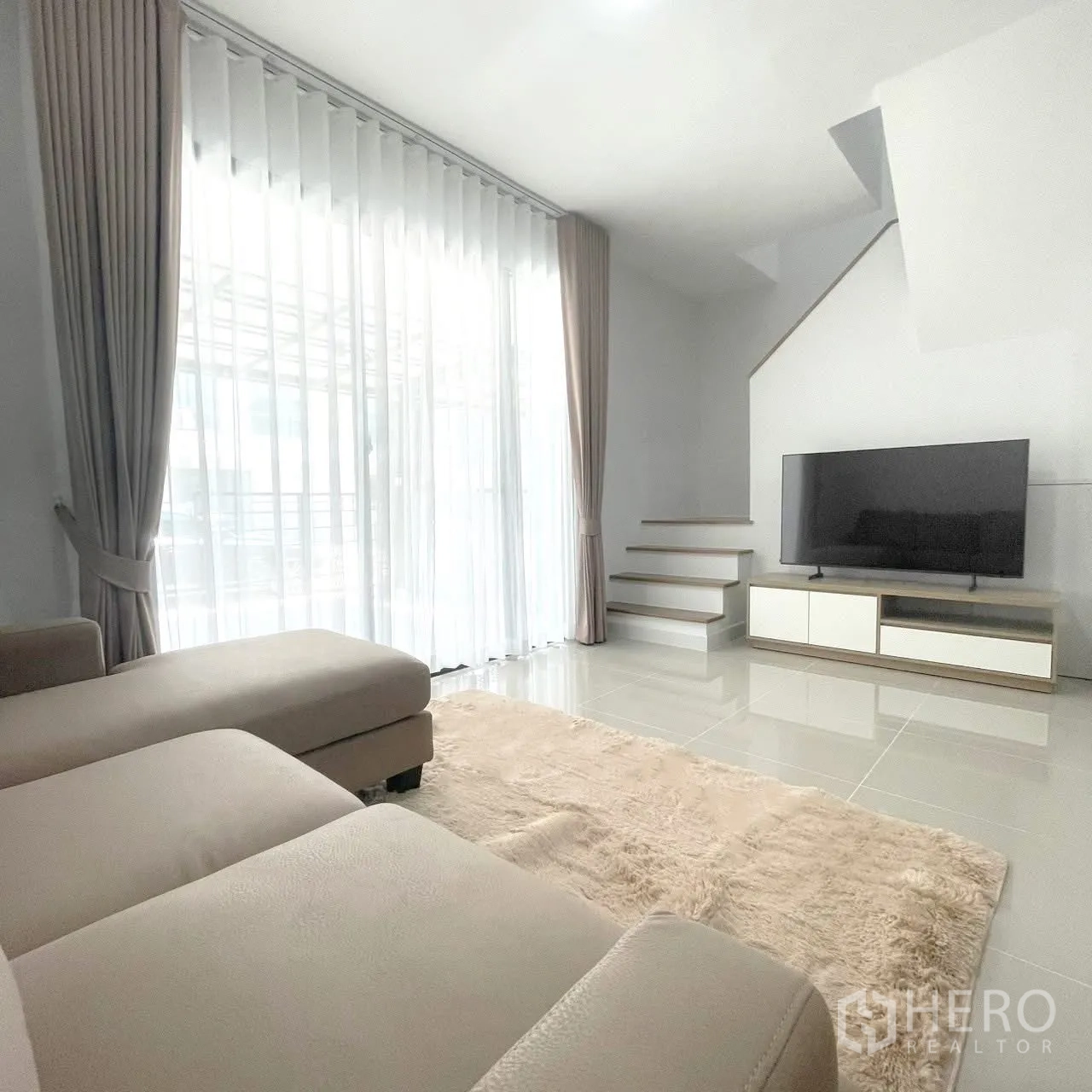 联排别墅 for rent in Bang Phli, Samut Prakan - 客厅设L型沙发、地毯、电视柜与楼梯背景