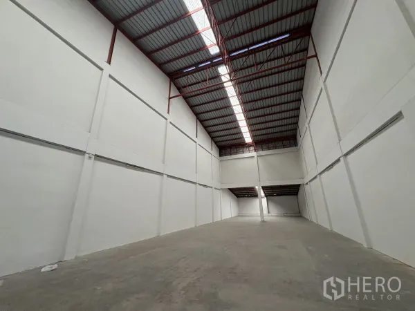 Factory for rent in Phra Samut Chedi, Samut Prakan - Long view of the warehouse showing skylights and tall white walls.