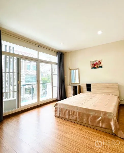 联排别墅 出租在Prawet, Bangkok - 明亮卧室，落地阳台门、木地板与窗帘