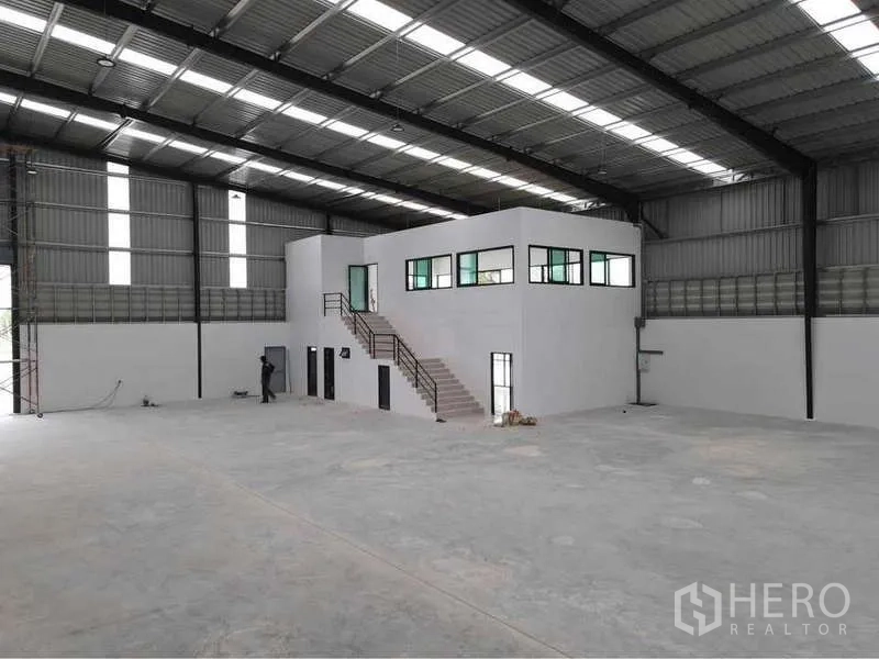 货栈 出租或出售在Nikhom Phatthana, Rayong - 仓库内部高挑钢结构，抛光混凝土地面，带楼梯的两层白色办公区。