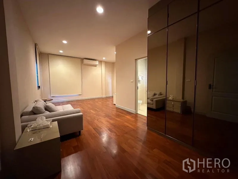 Detached House for rent or sale in Khan Na Yao, Bangkok - Bedroom with seating area, tall wardrobes and ensuite bathroom access.