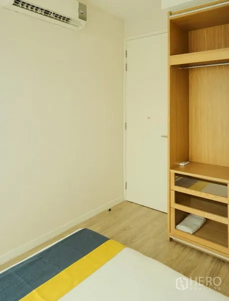 Condominium for rent in Bang Rak, Bangkok - Bedroom corner with built-in wardrobe shelves and air conditioner.
