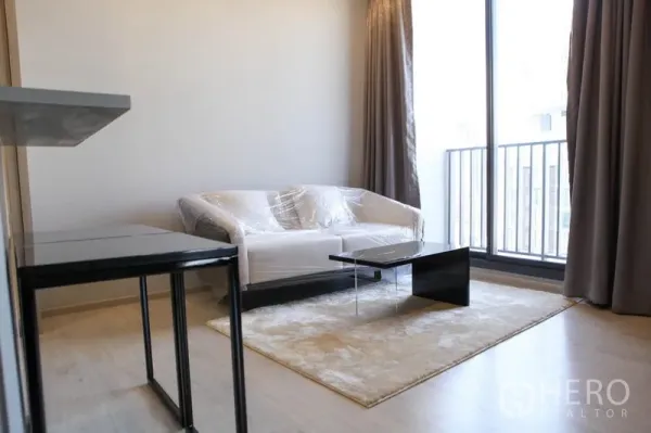 Condominium for rent in Watthana, Bangkok - Cozy living area with sofa, coffee table and floor-to-ceiling window to the balcony.